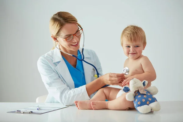 Médica feminina está ouvindo criança com um estetoscópio na clínica — Fotografia de Stock