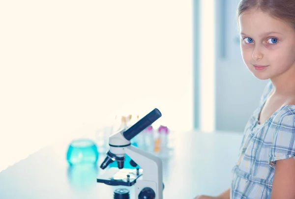 Colegiala mirando a través del microscopio en la clase de ciencias . — Foto de Stock