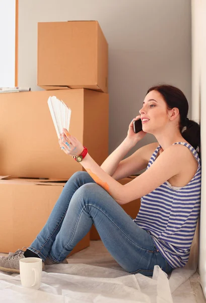 Woman choosing paint colour from swatch for new home sitting on wooden floor. Woman in the house — Stock Photo, Image