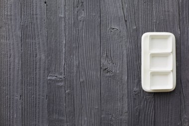 Beyaz tabakta taze kuşkonmaz servis edilir. Havan topu, ahşap masa arka planında. Üst manzara..