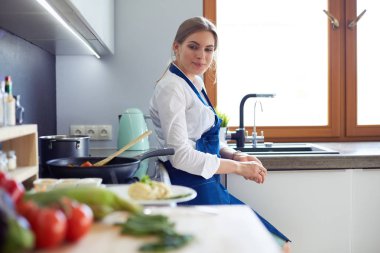 Mutfakta sobanın yanında duran genç bir kadın.