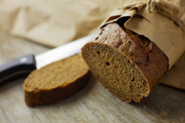 Tahta masanın üzerinde kağıda sarılı bir somun ekmek..