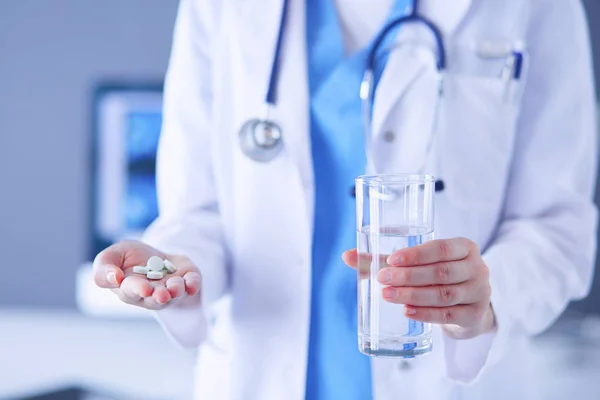 Colpo di mani di dottori che tengono pillole e vetro d'acqua a clinica. — Foto Stock