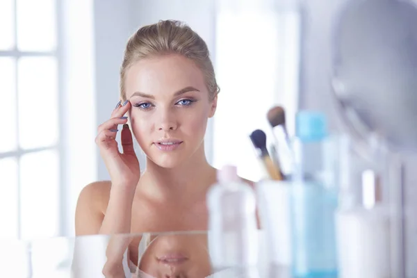 Jonge vrouw in badjas op zoek in badkamer spiegel — Stockfoto