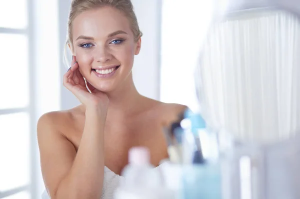 Giovane donna in accappatoio guardando nello specchio del bagno — Foto Stock