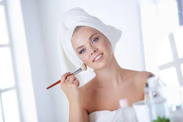 Zdjęcie młodej kobiety nakładającej proszek do twarzy w łazience — Zdjęcie stockowe