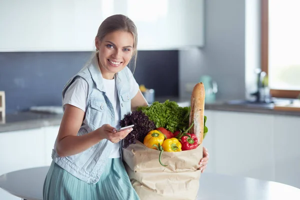 Молодая женщина держит продуктовый пакет с овощами. — стоковое фото
