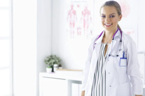 Medico femminile sorridente con uno stetoscopio medico in piedi uniforme — Foto Stock