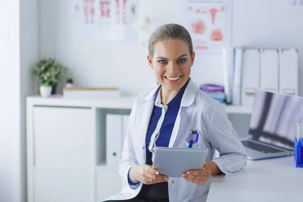 Hastane koridorundaki kadın doktorun portresi, elinde tablet bilgisayar, kameraya bakıyor, gülümsüyor. — Stok fotoğraf