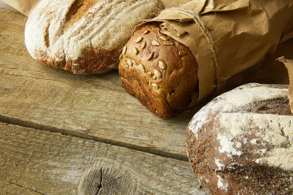 A loaf of Bread packed in paper on wooden table.