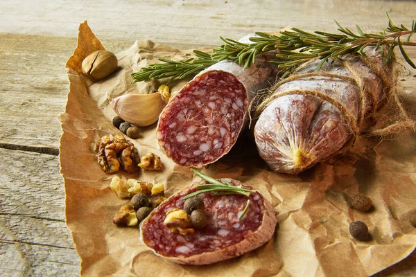 Italienische Salami mit Meersalz, Rosmarin, Knoblauch und Nüssen auf Papier. Rustikaler Stil. Nahaufnahme. — Stockfoto