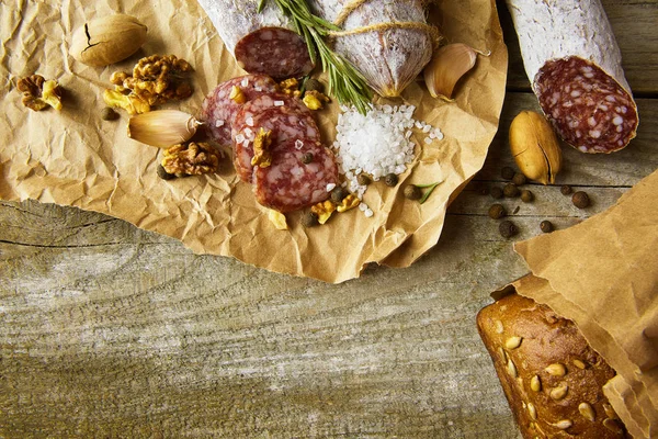 Italienische Salami mit Meersalz, Rosmarin, Knoblauch und Nüssen auf Papier. Rustikaler Stil. Ansicht von oben. — Stockfoto