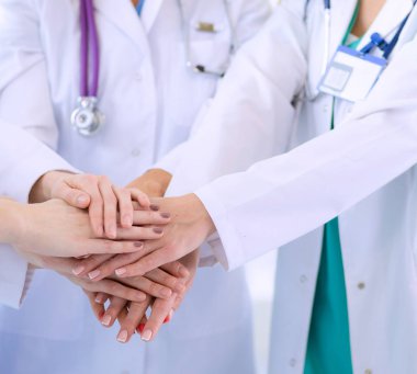 Doktorlar ve hemşireler tıbbi bir ekipte el ele tutuşuyorlar.