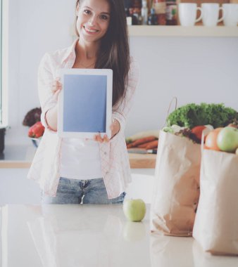 Mutfakta ipad 'ini kullanan genç bir kadın. Genç kadın.