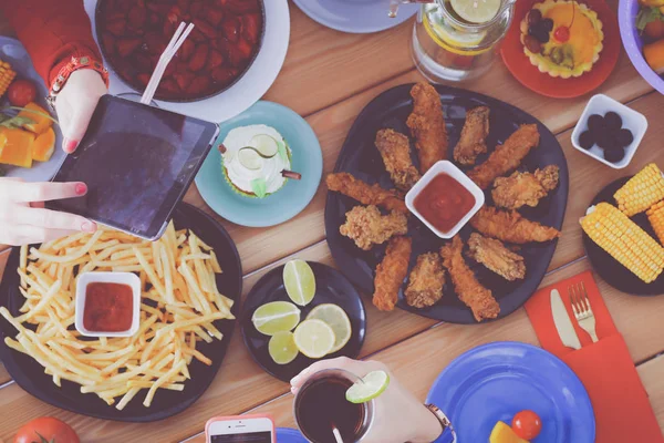 Vue du dessus du groupe de personnes qui dînent ensemble tout en étant assis à une table en bois. De la nourriture sur la table. Les gens mangent fast food. — Photo