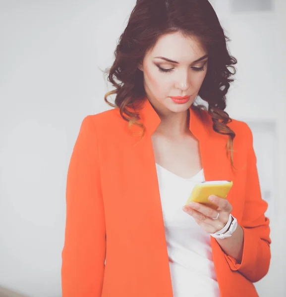 オフィスで立っている携帯電話を使用して美しい女性実業家 — ストック写真
