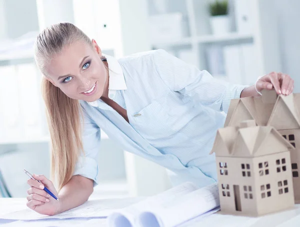 Portrait of female architect with blueprints at desk in office — Stock Photo, Image