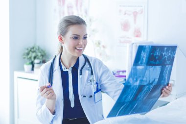 Genç ve çekici bayan doktor röntgen görüntülerine bakıyor.