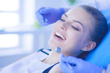 Dişçi muayenehanesinde diş muayenesi yapan ağzı açık genç bir kadın hasta..