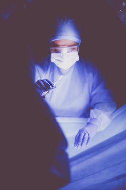 Doktor karanlık bir arka planda ameliyat yapıyor..