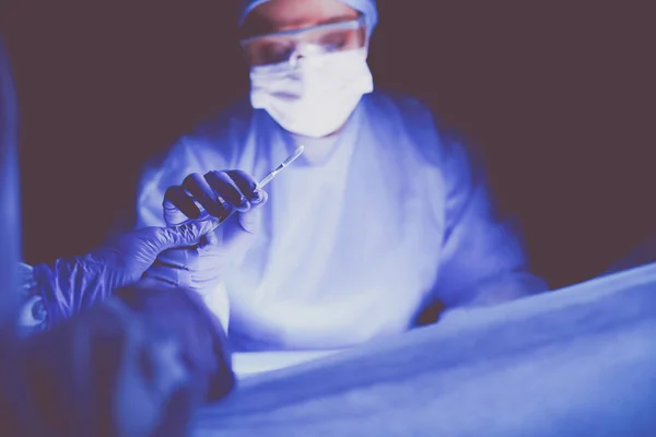 Médico realizando cirugía en un fondo oscuro. — Foto de Stock