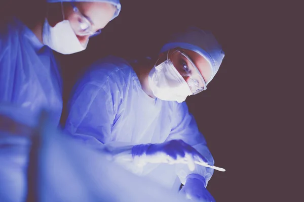 Equipo de médicos en cirugía en un fondo oscuro. — Foto de Stock