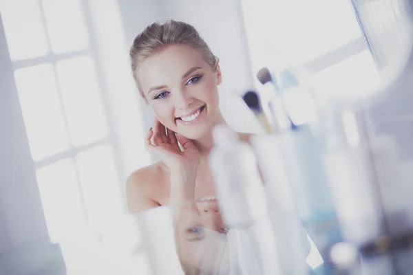 Giovane donna in accappatoio guardando nello specchio del bagno — Foto Stock