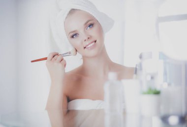 Genç bir kadının banyoya yüz pudrası sürerken fotoğrafı.