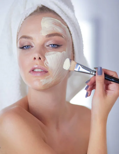 Una foto de una mujer joven aplicando polvo facial en el baño — Foto de Stock