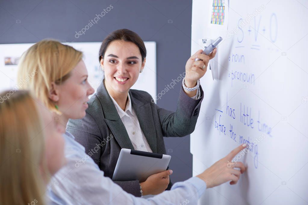 Business, education and office concept - business team with flip board in office discussing something.