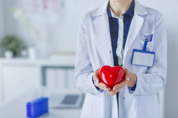Un médecin avec stéthoscope examinant le cœur rouge, isolé sur fond blanc — Photo