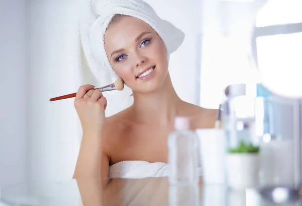 Uma foto de uma jovem mulher aplicando pó facial no banheiro — Fotografia de Stock