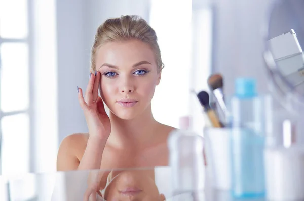 Jonge vrouw in badjas op zoek in badkamer spiegel — Stockfoto