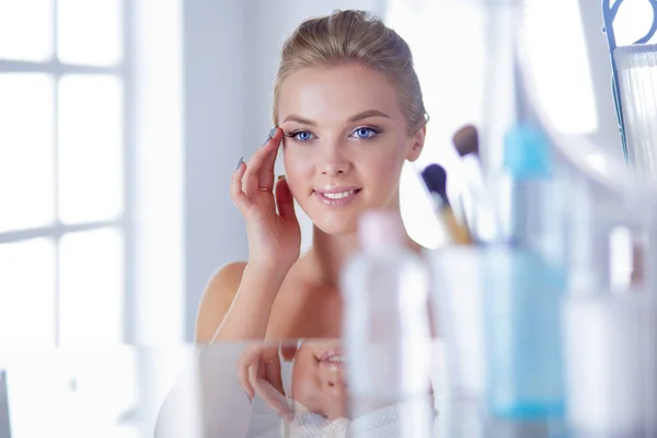 Young woman in bathrobe looking in bathroom mirror — Stock Photo, Image