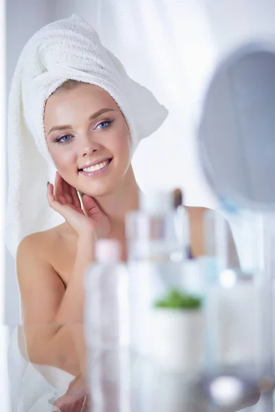 Jonge vrouw in badjas op zoek in badkamer spiegel — Stockfoto