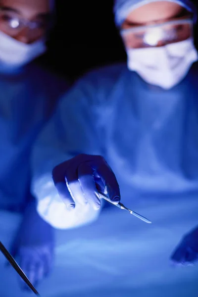 Photo recadrée du scalpel pris médecins effectuant une chirurgie. — Photo