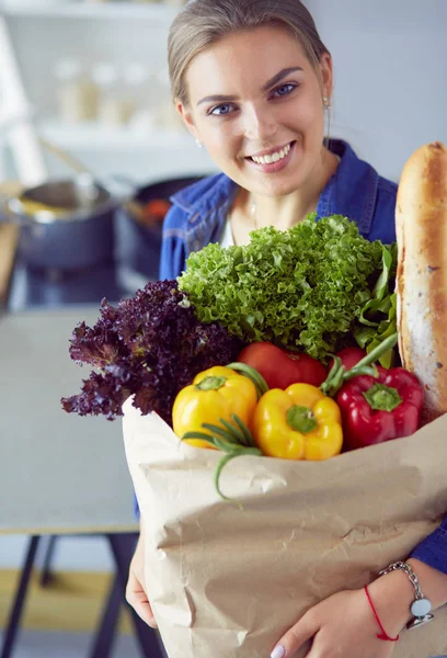 Jonge vrouw met boodschappentas met groenten.Staande in de keuken — Stockfoto