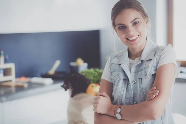 Portrait of young woman standing with arms crossed against kitchen background — Stock Photo, Image