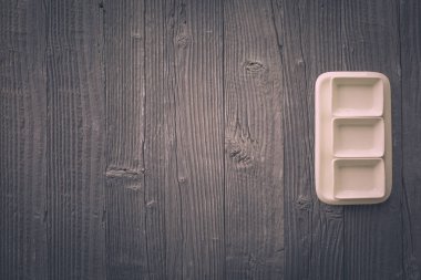 Beyaz tabakta taze kuşkonmaz servis edilir. Havan topu, ahşap masa arka planında. Üst manzara..