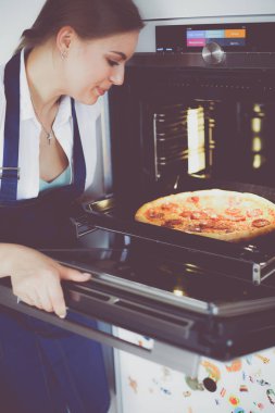 Mutlu genç bayan evde pizza pişiriyor.