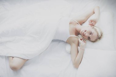 Güzel bir kadın yatağında uzanıyor.