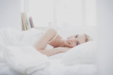 Güzel bir kadın yatağında uzanıyor.