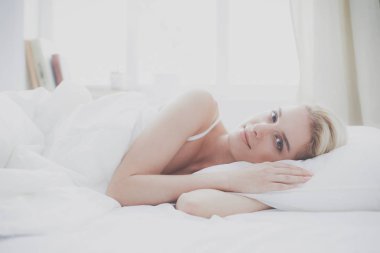 Güzel bir kadın yatağında uzanıyor.