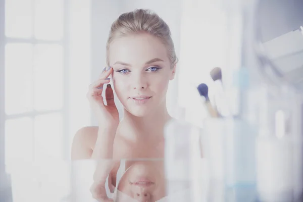 Young woman in bathrobe looking in bathroom mirror — Stock Photo, Image