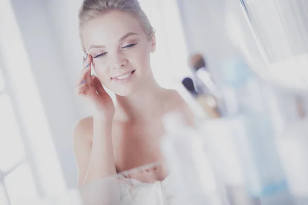Молодая женщина в халате смотрит в зеркало ванной комнаты — стоковое фото