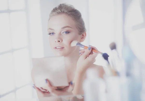 A picture of a young woman applying face powder in the bathroom — Stock Photo, Image