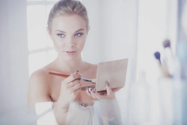 A picture of a young woman applying face powder in the bathroom — Stock Photo, Image