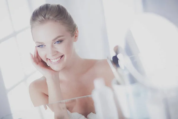 Jonge vrouw in badjas op zoek in badkamer spiegel — Stockfoto