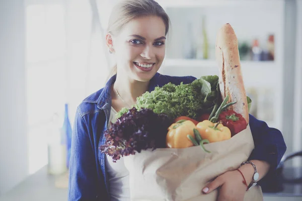 Young woman holding grocery shopping bag with vegetables .Standing in the kitchen — Stock Photo, Image