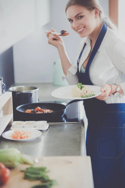 Mujer joven parada junto a la estufa en la cocina — Foto de Stock